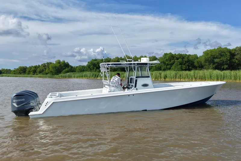 Slide: The Image of 2013 Contender 39 ST boat on calm water with Yamaha engine, lush greenery in background. - 13
