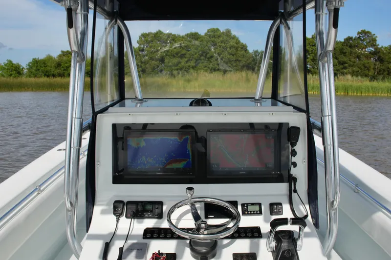 Slide: The Image of 2013 Contender 39 ST boat dashboard with navigation screens and controls on a calm waterway. - 35