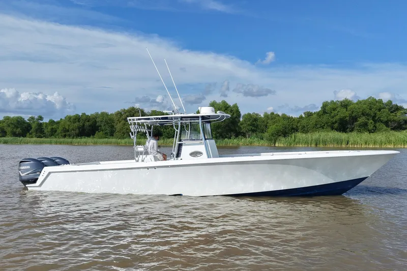 Slide: The Image of 2013 Contender 39 ST boat on water with Yamaha engines, clear sky, and lush greenery. - 10