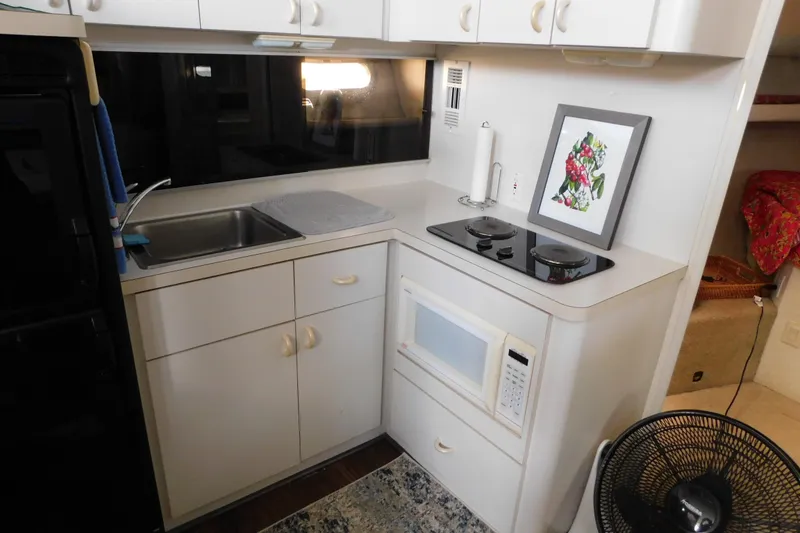 Slide: The Image of Compact kitchen in a 1992 Silverton 41 Aft Cabin yacht with sink, stove, and microwave. - 60