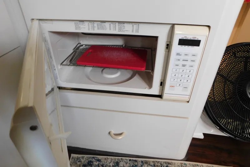 Slide: The Image of Microwave oven with open door, red cutting board inside, on a 1992 Silverton 41 Aft Cabin. - 65