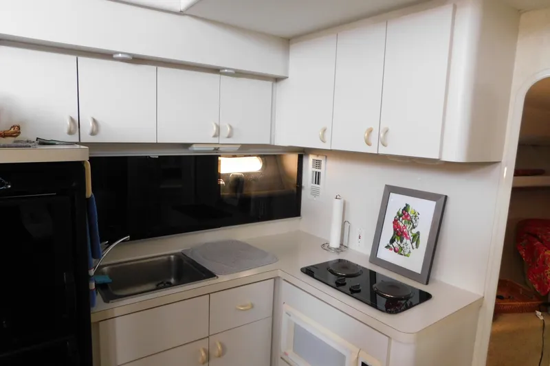 Slide: The Image of 1992 Silverton 41 Aft Cabin kitchen with white cabinets, sink, and stovetop. - 61