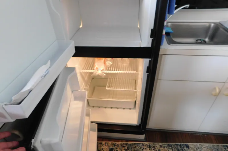 Slide: The Image of Open refrigerator in 1992 Silverton 41 Aft Cabin yacht kitchen, showing interior shelves and sink nearby. - 67