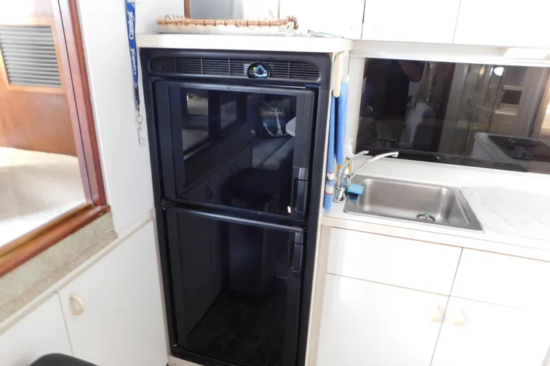 Slide: The Image of 1992 Silverton 41 Aft Cabin kitchen with black fridge and stainless steel sink. - 62