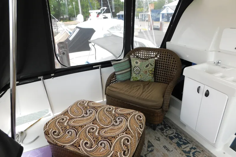 Slide: The Image of Interior of 1992 Silverton 41 Aft Cabin with wicker chair, patterned ottoman, and sink. - 10