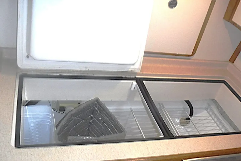 Slide: The Image of Open refrigerator compartment in a 1998 Catalina 320 yacht, showcasing storage space. - 38