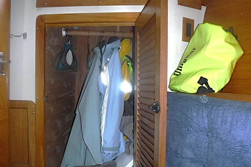 Slide: The Image of Closet inside a 1998 Catalina 320 sailboat with hanging clothes and a yellow dry bag. - 62