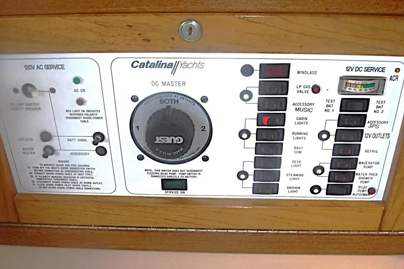 Slide: The Image of Control panel of a 1998 Catalina 320 yacht, featuring AC and DC service switches. - 42