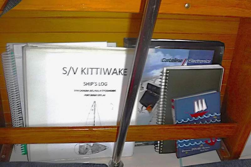Slide: The Image of Shelf with ship's log and manuals for 1998 Catalina 320 sailboat. - 45