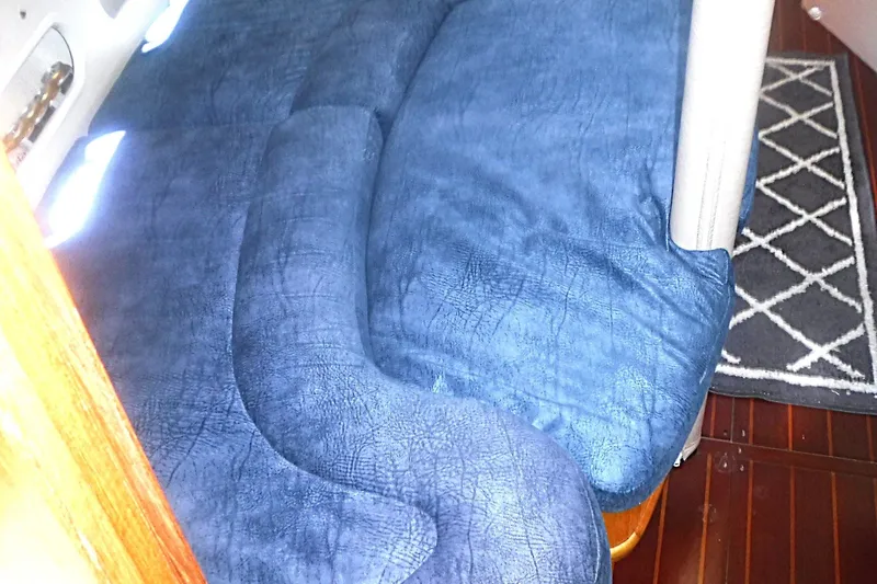 Slide: The Image of Blue cushioned seating inside a 1998 Catalina 320 sailboat cabin. - 54