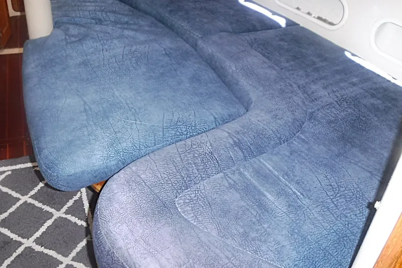 Slide: The Image of Blue cushioned seating inside a 1998 Catalina 320 sailboat cabin. - 53