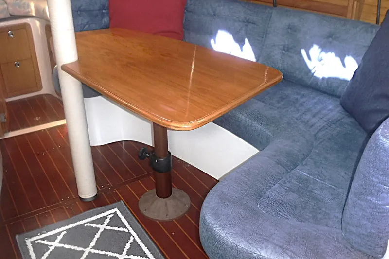 Slide: The Image of Interior of a 1998 Catalina 320 sailboat with wooden table and blue seating. - 51