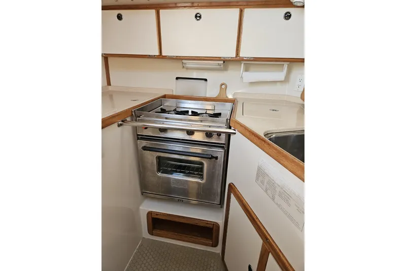 Slide: The Image of Compact kitchen area in a 1998 Catalina 320 sailboat, featuring a stainless steel stove and oven. - 36