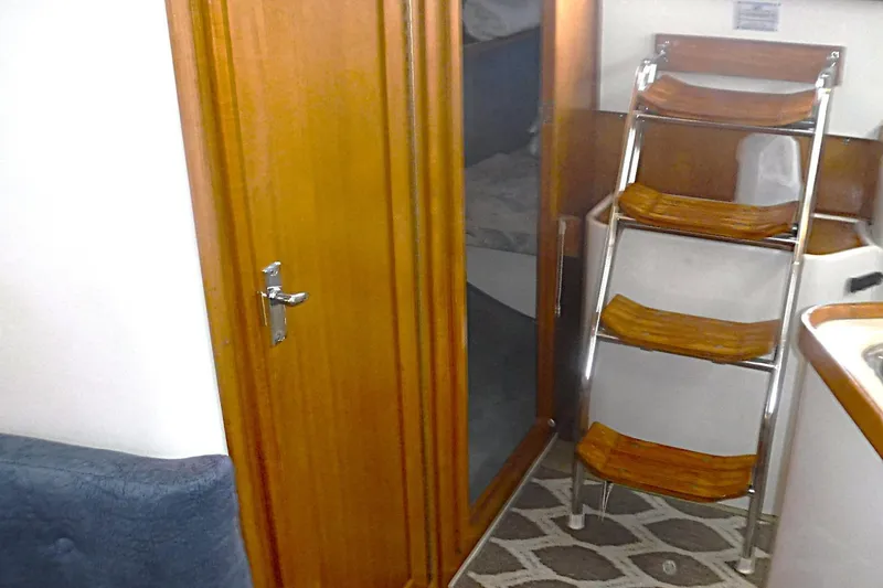 Slide: The Image of Interior of a 1998 Catalina 320 sailboat featuring wooden cabinetry and a compact ladder. - 53