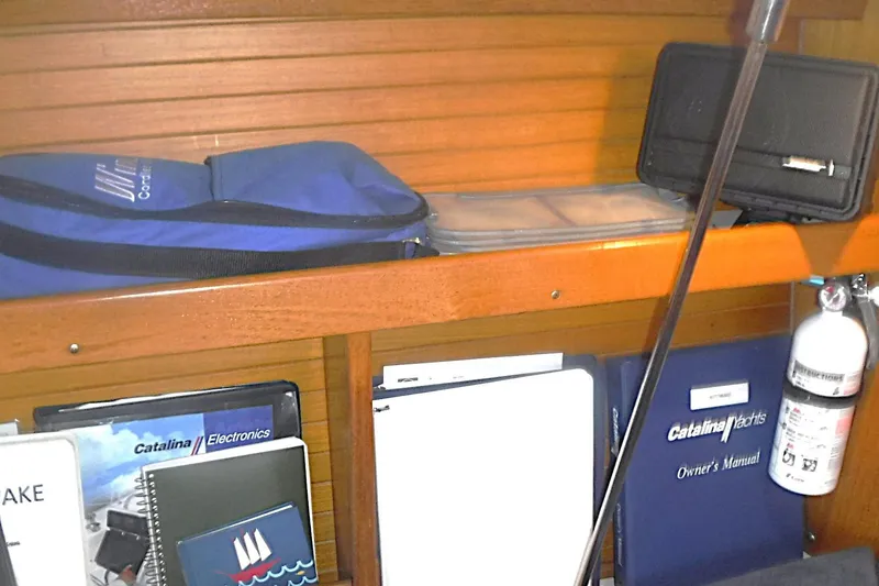 Slide: The Image of Shelving with Catalina 320 manuals, electronics guides, and safety equipment on a 1998 model yacht. - 46