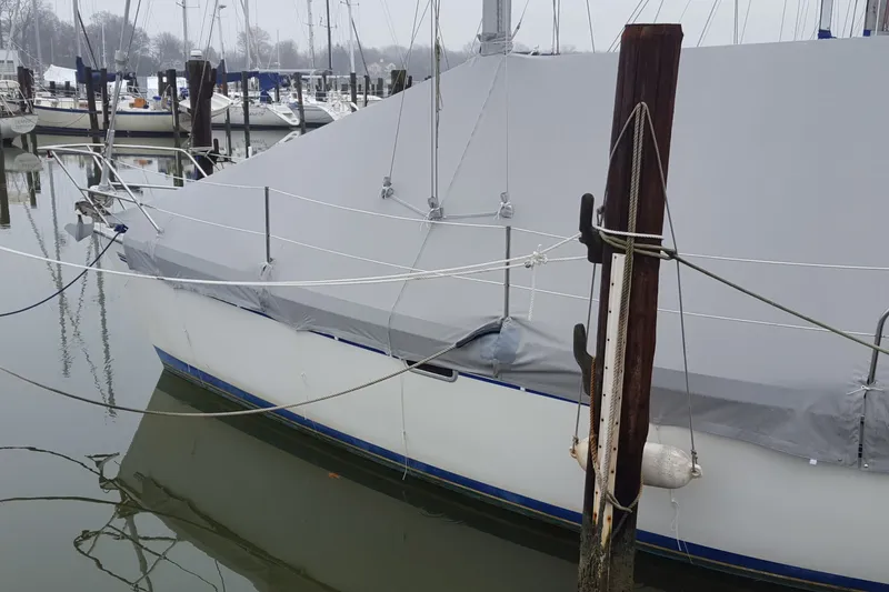 Slide: The Image of 1998 Catalina 320 sailboat docked, covered with a protective tarp in a marina. - 6