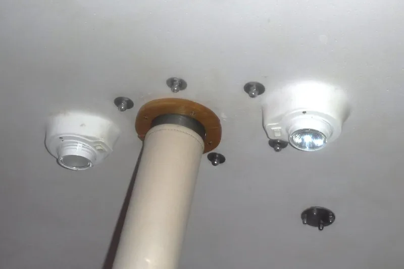 Slide: The Image of Ceiling view inside 1998 Catalina 320 sailboat, featuring lights and a support pole. - 82