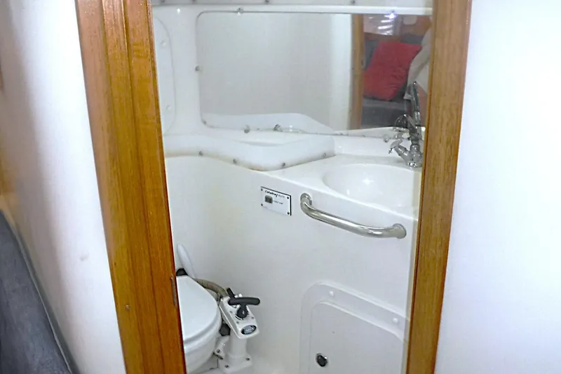 Slide: The Image of Compact bathroom in a 1998 Catalina 320 sailboat, featuring a toilet and sink. - 65