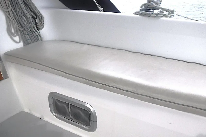 Slide: The Image of Interior seating of a 1998 Catalina 320 sailboat with white cushion and window vent. - 29