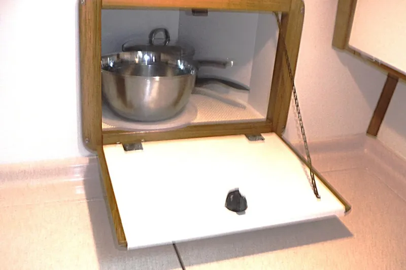 Slide: The Image of Cabinet with open door revealing cookware inside a 1998 Catalina 320 sailboat. - 39