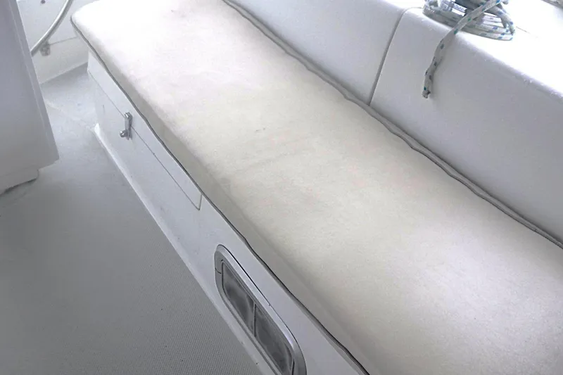 Slide: The Image of Interior seating area of a 1998 Catalina 320 sailboat, featuring white cushioned bench. - 28