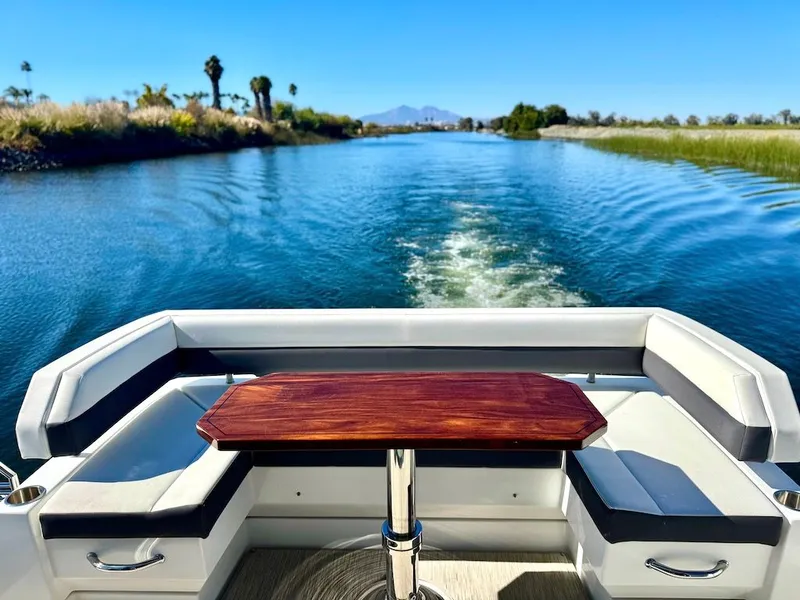 Slide: The Image of Aft view of a luxury yacht with a sleek wooden table and cushioned seating on a calm river. - 7