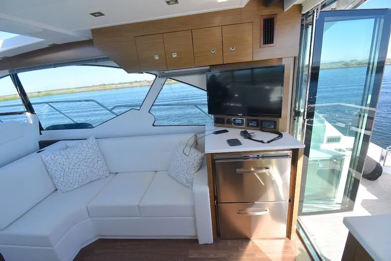 Slide: The Image of Interior of a 2019 Cruisers Yachts 50 Cantius with white sofa, TV, and water view. - 13