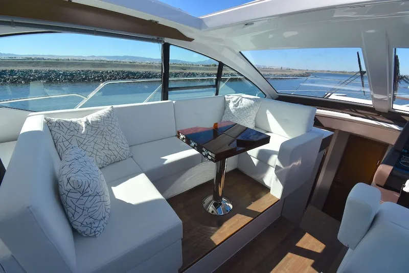 Slide: The Image of The image shows the interior of a 2019 Cruisers Yachts 50 Cantius with sleek white sofas and a wooden table. - 19