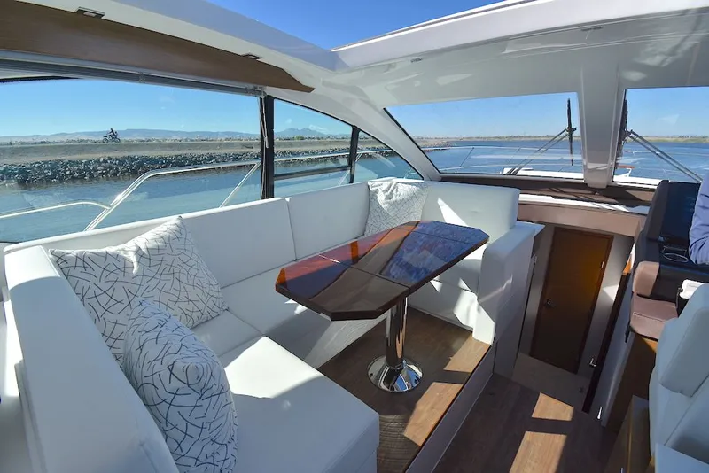 Slide: The Image of Interior of the 2019 Cruisers Yachts 50 Cantius with sleek white upholstery and a wooden table. - 20
