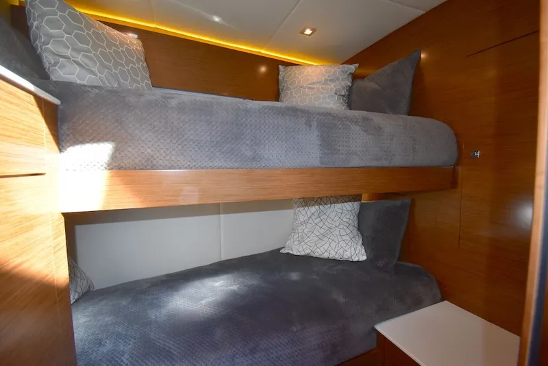 Slide: The Image of Cabin with bunk beds and gray bedding, wooden walls, and soft lighting. - 21