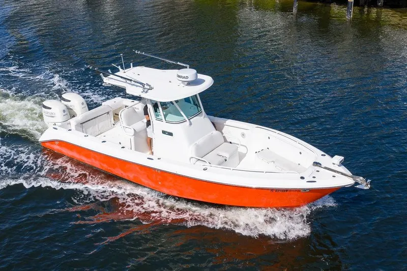 Slide: The Image of 2006 Everglades 290 Center Console boat with orange hull cruising on water. - 2
