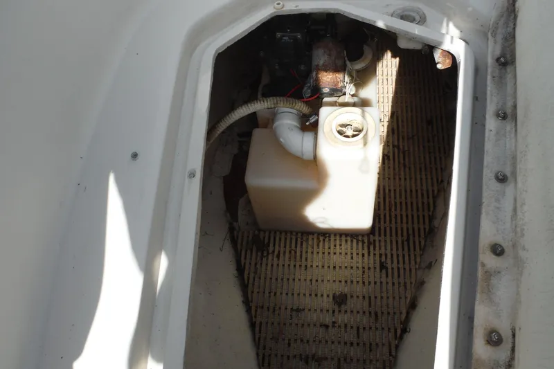 Slide: The Image of Storage compartment of a 2005 Sea Ray 240 Sundeck boat, featuring a white plastic container. - 23