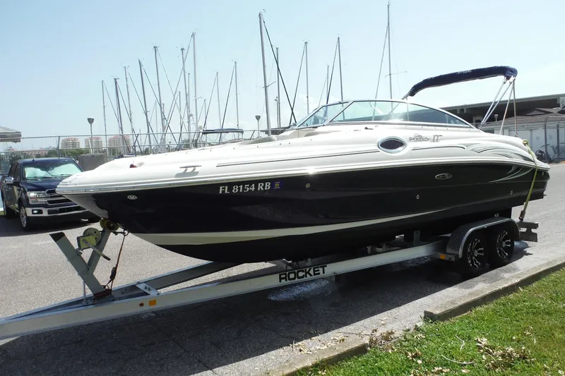 Slide: The Image of 2005 Sea Ray 240 Sundeck boat on trailer, parked near marina with sailboats. - 42