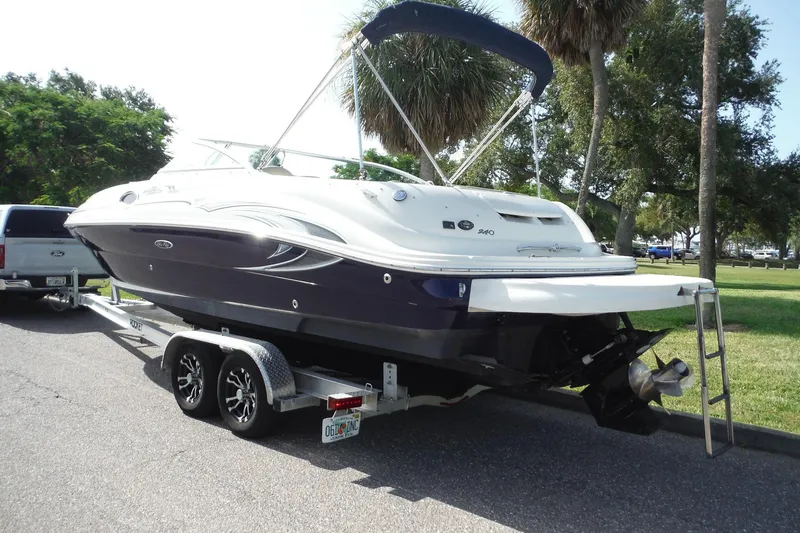 Slide: The Image of 2005 Sea Ray 240 Sundeck boat on trailer, parked near trees and grass. - 3