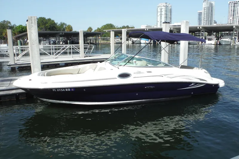 Slide: The Image of 2005 Sea Ray 240 Sundeck boat docked at marina with city skyline background. - 26
