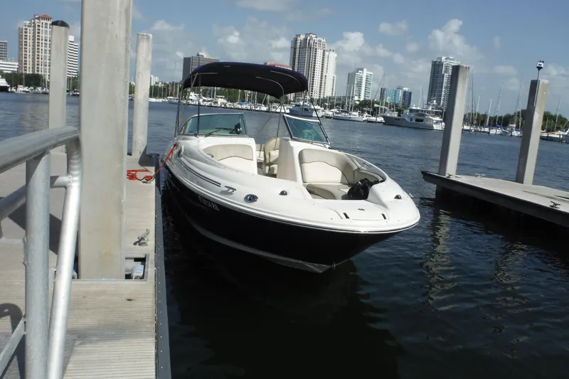 Slide: The Image of 2005 Sea Ray 240 Sundeck docked at marina with city skyline in background. - 28
