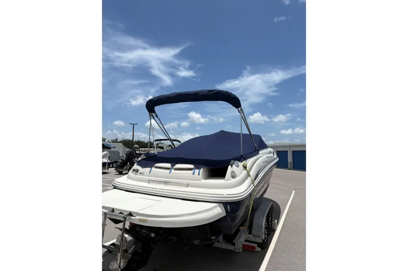Slide: The Image of 2005 Sea Ray 240 Sundeck boat with blue cover on trailer under clear sky. - 34