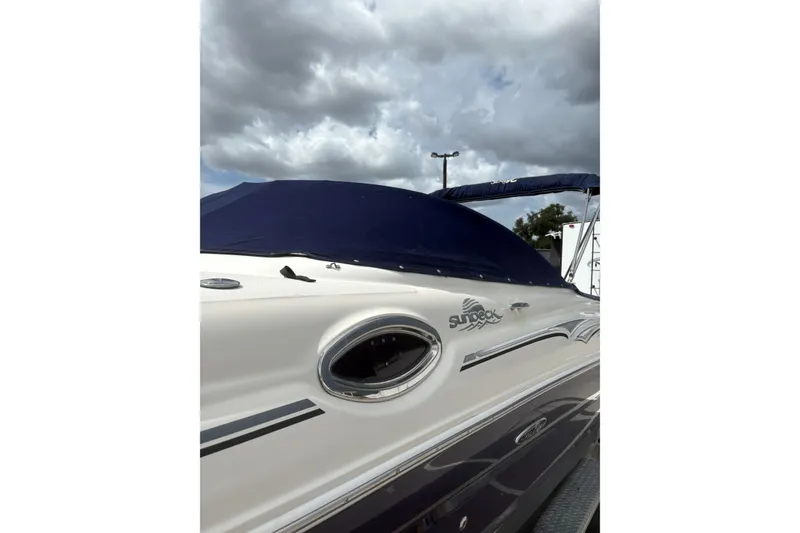 Slide: The Image of 2005 Sea Ray 240 Sundeck boat with blue cover under cloudy sky. - 35