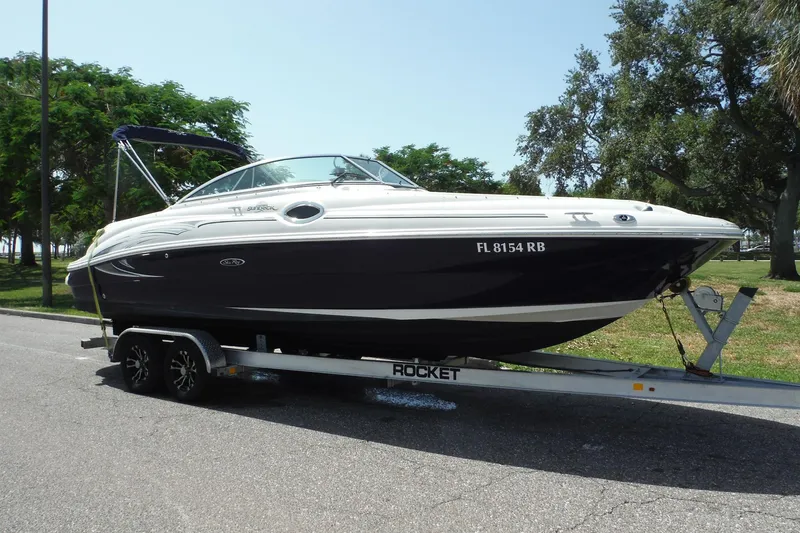 Slide: The Image of 2005 Sea Ray 240 Sundeck boat on trailer, parked outdoors with trees in background. - 38