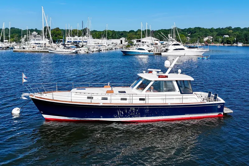 The Image of 2001 Grand Banks 49 Eastbay HX yacht on calm water, marina in background. - 0