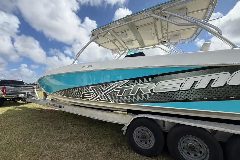 Slide: The Image of 2016 Extreme Boats XC38 on trailer, vibrant blue and white design under cloudy sky. - 36