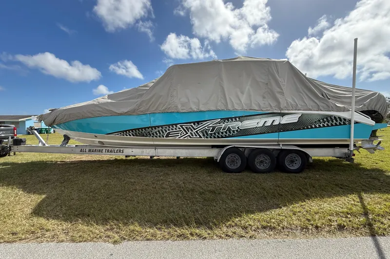 Slide: The Image of 2016 Extreme Boats XC38 on trailer, covered, parked on grass under blue sky. - 5
