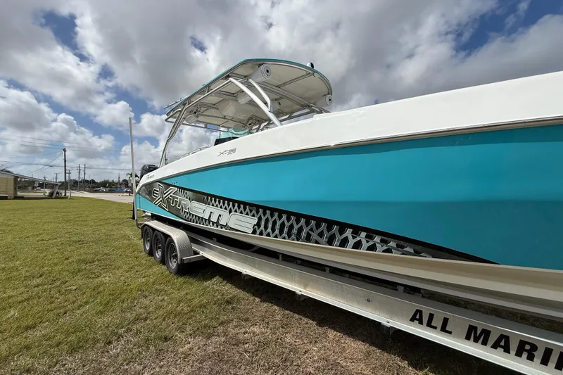 Slide: The Image of 2016 Extreme Boats XC38 on trailer, vibrant blue and white design, parked on grass under cloudy sky. - 19