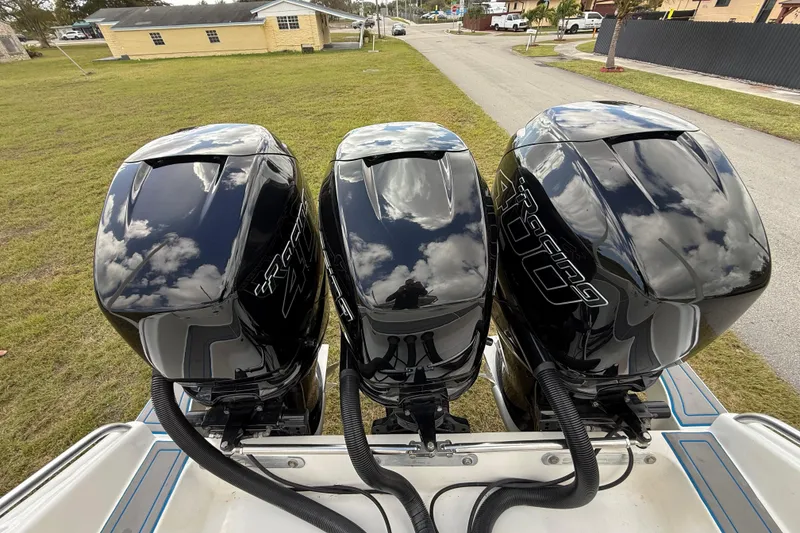 Slide: The Image of Triple outboard motors on a 2016 Extreme Boats XC38, reflecting clouds. - 77