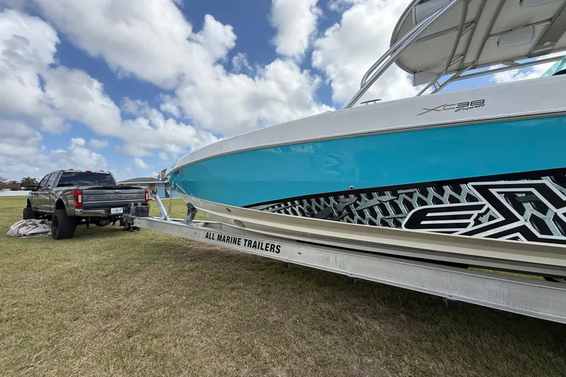 Slide: The Image of 2016 Extreme Boats XC38 on trailer, parked beside a truck under a cloudy sky. - 38