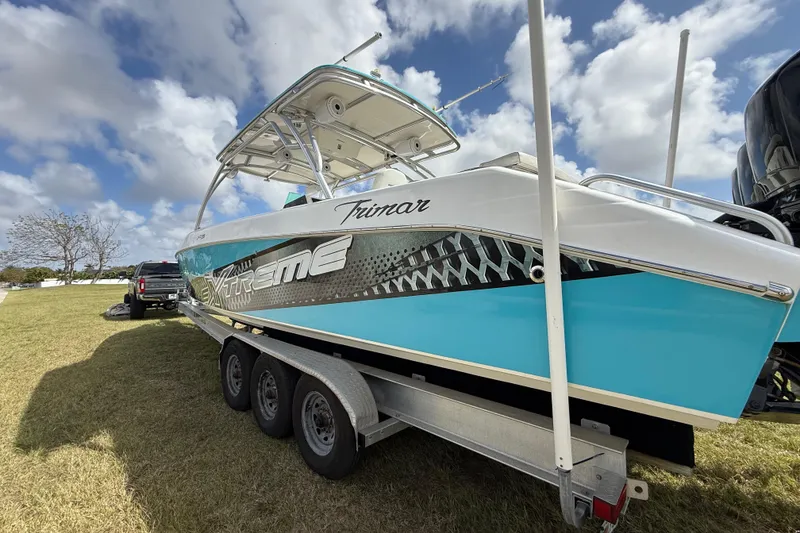 Slide: The Image of 2016 Extreme Boats XC38 on trailer, vibrant blue and white design, parked on grass under cloudy sky. - 33