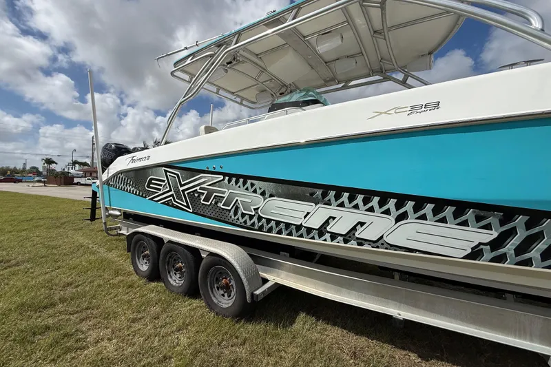 Slide: The Image of 2016 Extreme Boats XC38 on trailer, vibrant blue and white design, parked on grass. - 22