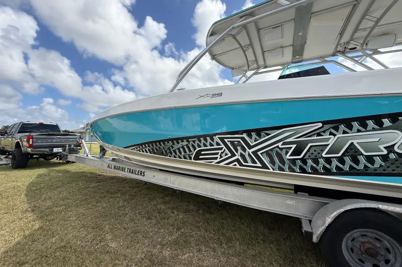 Slide: The Image of 2016 Extreme Boats XC38 on trailer, vibrant blue design, parked on grass under cloudy sky. - 37