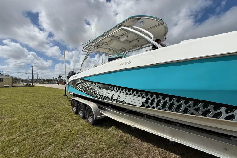 Slide: The Image of 2016 Extreme Boats XC38 on trailer, vibrant blue and white design under cloudy sky. - 20