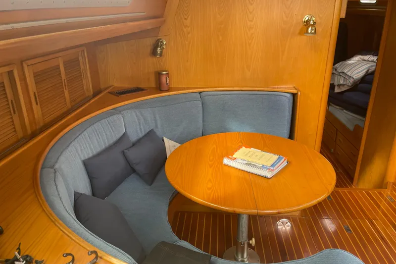 Slide: The Image of Cozy dining area on 1985 Hinckley Sou'wester 59 yacht with wooden table and blue seating. - 12